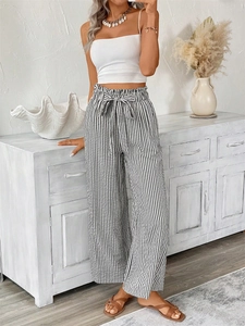 Detail of paper-bag waist with tie-up bow on black and white vertical striped trousers