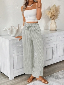 Detail of high-waisted striped wide-leg trousers with elegant bow-tie waist strap