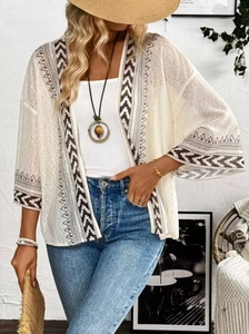 Détail du cardigan en maille crème avec motifs géométriques sur les manches évasées