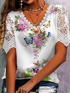 Detail of V-neck white top featuring floral lace sleeves and vibrant butterfly print