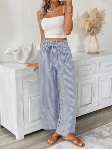 Detail of high-waist paperbag trousers with blue stripes and a matching waist tie bow