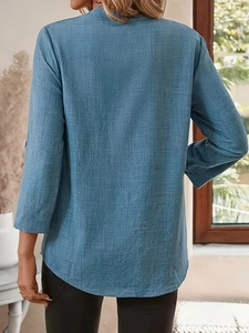 Detail view of the curved hem and textured blue fabric on women's long sleeve V-neck top