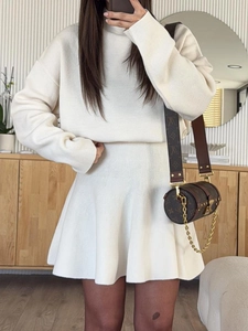 Close-up of cream white knit texture on high collar long sleeve top and skirt