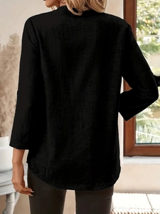 Detail of black V-neck long sleeve top showing breathable linen texture and curved hemline