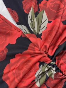 Detail of V-neckline and ruching on a floral print dress with red roses on black