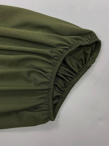 Detailed close-up of olive green ribbed fabric with elastic smocked cuff and neat stitching