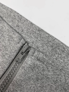 Detailed close-up of gray knitted fabric texture and matching zipper closure on garment