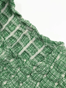 Detailed macro view of green and white textured seersucker fabric with neat stitching