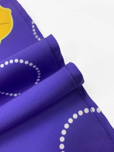 Detail of purple printed fabric with yellow patterns and precise stitching on the edge