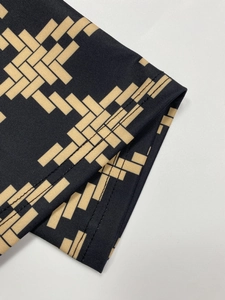 Detail of flared pants showing black and gold geometric knit fabric and neat stitching