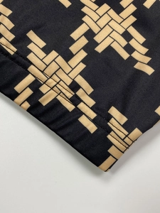Close-up of black flare pants with gold geometric pattern and flat double-needle stitching