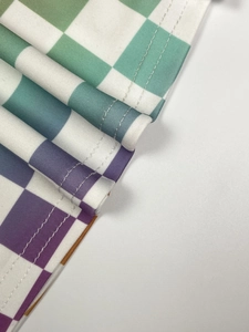 Détail du tissu à damier dégradé avec double couture précise sur le pantalon évasé