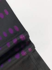 Detail of black fabric with purple polka dots showing high quality stitching and texture