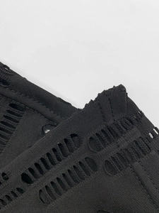Gros plan détaillé du tissu en maille noire avec découpes ovales et texture tricotée pour robe