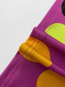 Detail of vibrant purple fabric with large yellow dots and double-needle coverstitch sewing