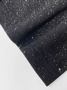 Detailed macro view of black knit fabric with silver sequins and finished hem stitching