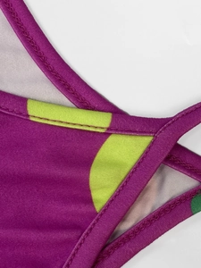Detail of purple dress fabric with lime green polka dots and fine stitching seams