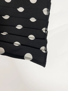 Detail of white polka dot fabric with pleated texture and fine black hem stitching