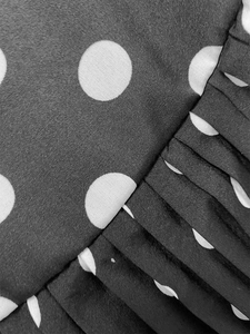 Macro detail of black and white polka dot fabric with dense parallel pleats for women dress