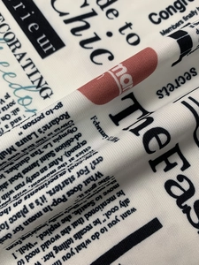 Detalle de tela ligera con estampados de periódico y detalles circulares rojos
