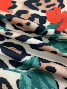 Detail of floral and leopard print fabric with red flowers and green leaves pattern