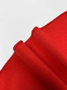 Detail shot of bright red knit dress featuring professional overlock stitching and wavy hem