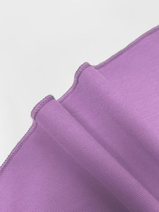 Detailed close-up showing the purple fabric texture and refined overlock stitching details