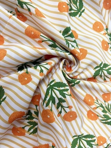 Close-up of lightweight floral fabric with orange blossoms and yellow stripes