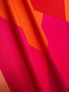 Detailed macro view of colorful geometric patchwork fabric with warm reddish tones