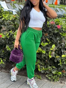 Women's plus size white crop top and green drawstring sweatpants with plush purple handbag