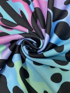 Detailed view of colorful camo floral print fabric with polka dots on soft knit material