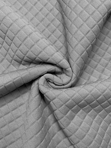 Macro detail of soft light gray quilted fabric with diamond textured knit pattern