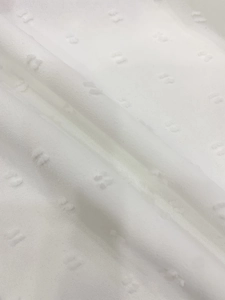Detailed macro view of white Swiss dot fabric with soft translucent chiffon texture