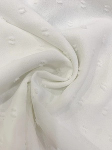 Detailed close-up of white Swiss dot fabric showing breathable texture and drapery