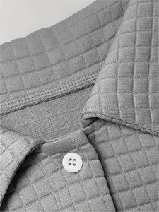 Close-up of grey waffle knit polo shirt showing textured fabric and white resin button detail
