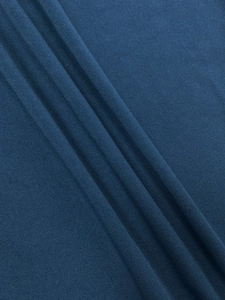 Macro shot of dark blue textured knit fabric showing material detail and soft draping