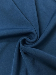 Close-up of deep blue knitted fabric with fine ribbed texture and soft fold details