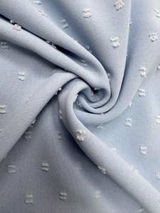 Macro view of light blue chiffon fabric featuring white textured polka dot patterns