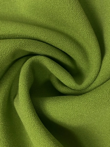 Detailed macro view of grass green chiffon fabric with fine grainy texture and elegant drape