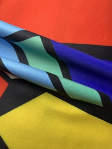 Detailed close-up of colorful geometric print fabric with vibrant twill texture for dresses