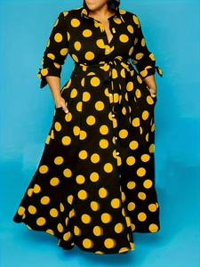 Close-up of black shirt dress with yellow polka dots, bow cuffs and matching waist tie