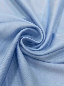 Detailed close-up of light blue fabric texture with soft silky sheen and elegant folds