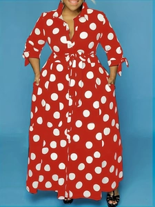 Detail of red long-sleeved dress with white polka dots featuring shirt collar and belt