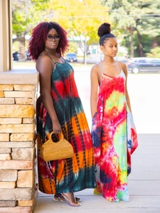 Detail of loose tie-dye maxi dresses featuring vibrant patterns and side pockets
