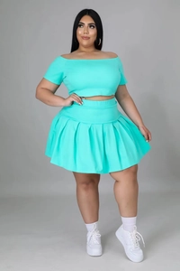 Detail of mint green off-shoulder crop top and high-waisted pleated mini skirt set