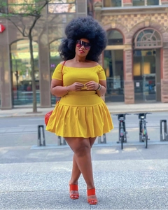 Detailed outdoor shot of the bright yellow off-shoulder top and pleated mini skirt set