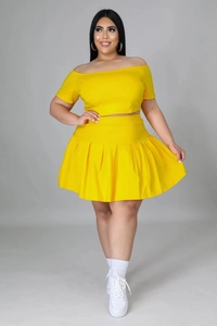 Detail view of yellow two-piece set featuring off-shoulder crop top and pleated mini skirt