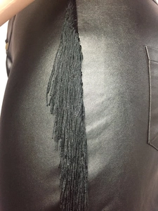 Detailaufnahme der schwarzen Lederhose mit hoher Taille, langen Fransen und Seitentasche