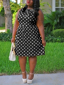 Outdoor shot of a plus size sleeveless A-line dress with black and white polka dot pattern