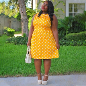 Detail of a bright yellow polka dot plus-size dress with a stylish neckline bow